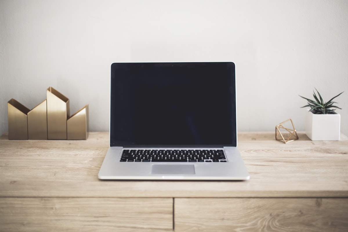 Laptop siendo limpiada con paño de microfibra y spray desinfectante para electrónicos