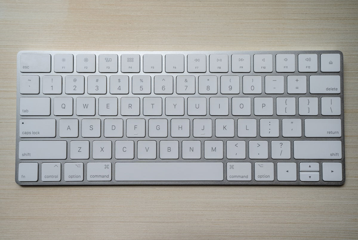 Teclado de computadora siendo limpiado con spray desinfectante y paño de microfibra